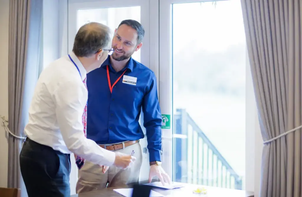 Two men talking during networking event near window